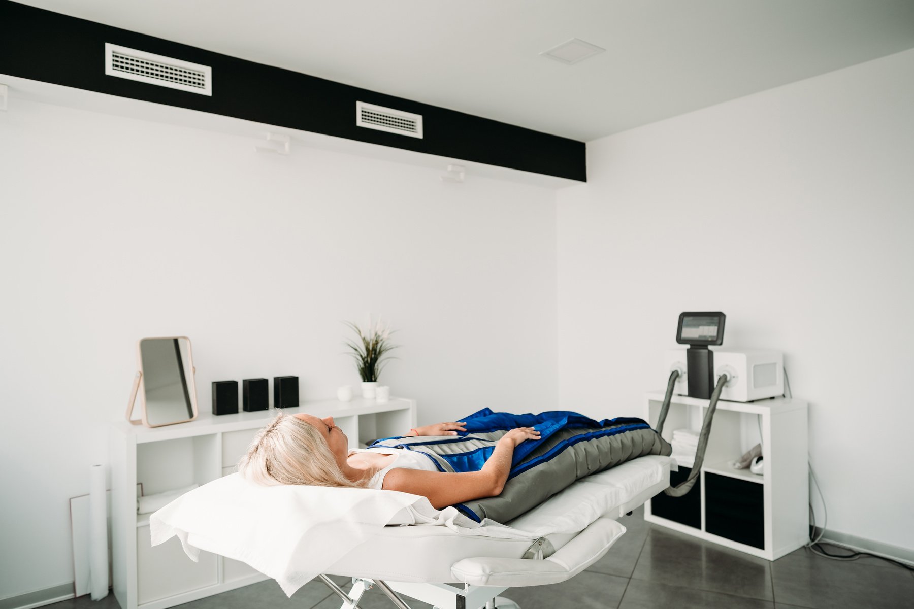 Relaxed woman enjoying in pressotherapy treatment at wellness center.